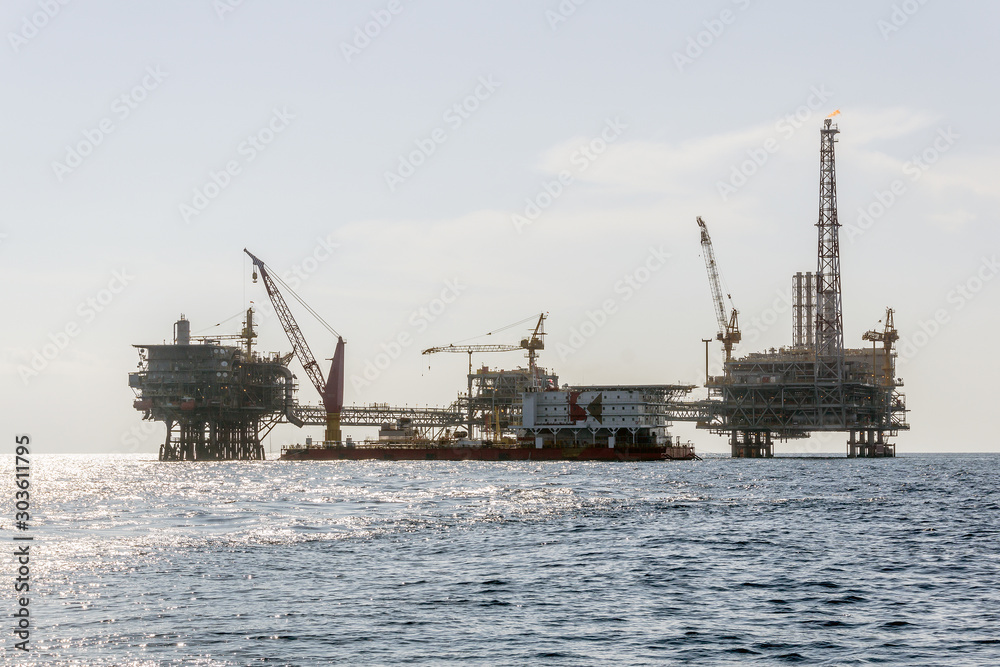 A construction work barge moored near an oil production platforms at oil field