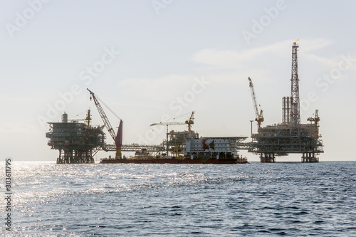 A construction work barge moored near an oil production platforms at oil field © wanfahmy