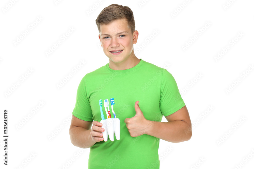 Young man holding toothbrushes and showing thumb up isolated on white background Young man holding toothbrushes and showing thumb up isolated on white background
