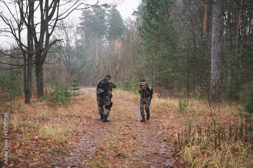 Two military men with machine guns and camouflage in the forest