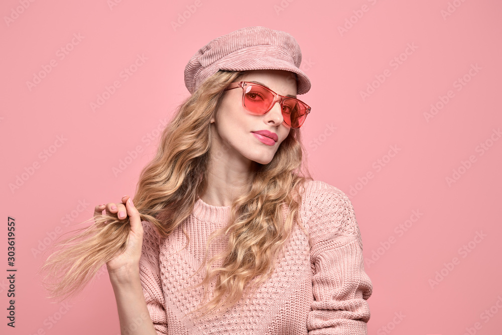 Fashionable lovable woman in Trendy pink outfit, stylish hairstyle, makeup smiling. Young blonde in jumper. Sensual beautiful model girl in stylish sunglasses, pastel fashion beauty concept on pink Fashionable lovable woman in Trendy pink outfit, stylish hairstyle, makeup smiling. Young blonde in jumper. Sensual beautiful model girl in stylish sunglasses, pastel fashion beauty concept on pink