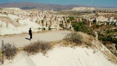 Woman walking towards the edge of a cliff in Love Valley, Cappadocia, Turkey. Aerial left to right pan with woman center frame photo