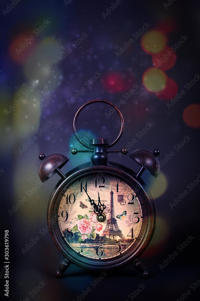 An old vintage clock with sparkles on a black background