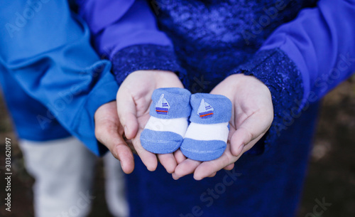 Parents holding baby shoes in their palm