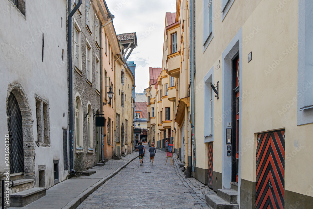 Medieval narrow street of Tallinn Old Town with cobblestone pavement.