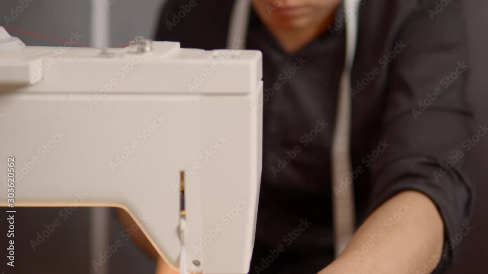 A young latino fashion designer sewing on his sewing machine. Tilt up shot with focus racking A young latino fashion designer sewing on his sewing machine. Tilt up shot with focus racking