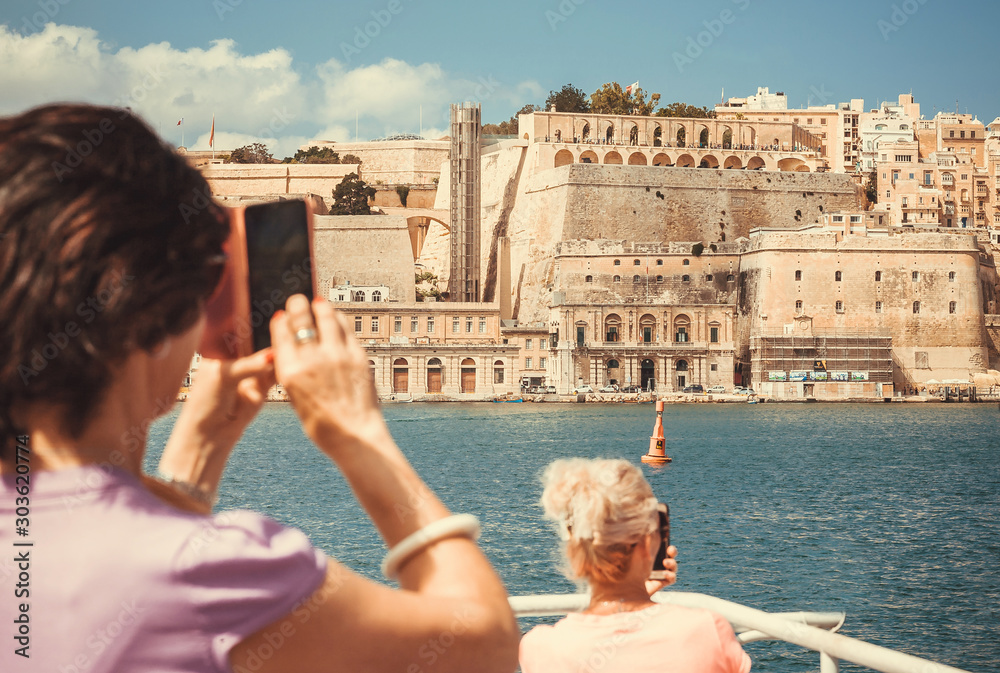 Φωτογραφία Sea boat with crowd of curious tourists near Valletta city fortified walls