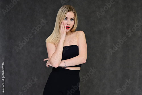 Fashion glamor concept with girl secretary. Portrait of a fashionable beautiful blonde model with long hair, great makeup, on a gray background.