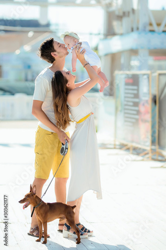 young stylish hipster couple in love walking playing dog puppy in tropical beach, white sand, cool outfit, romantic mood, having fun, sunny, man woman together, horizontal, vacation.