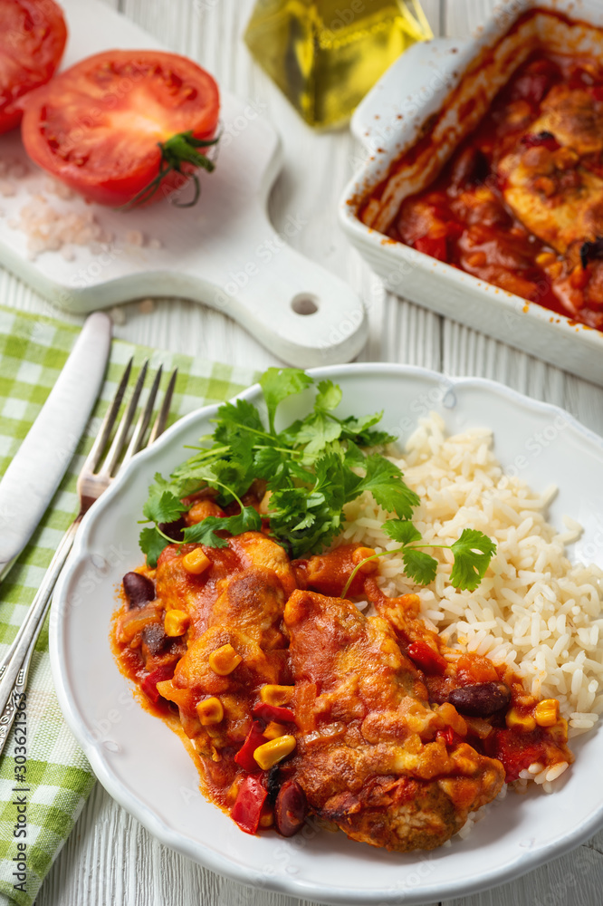 Chicken fillet baked in tomato sauce with corn and beans, served with boiled rice. Mexican style cuisine.