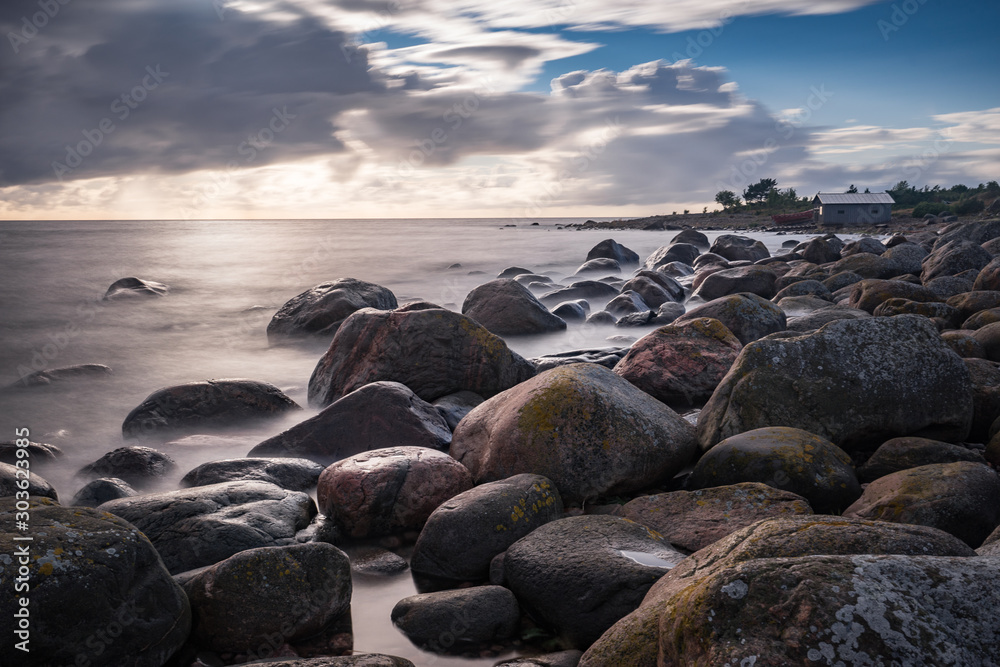 Boulders, forest, shore, evening light, sunset, clouds, blue sky and rainbow on the Baltic Sea. Mohni, small island in Estonia, Europe.
