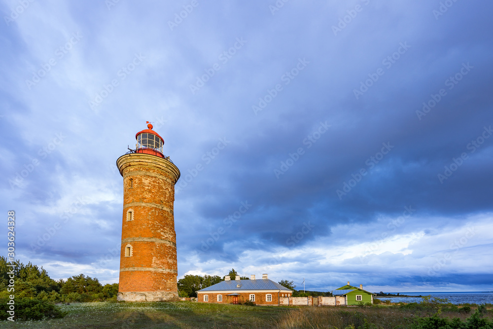 Lighthouse and house in the Baltic Sea. Shore, evening light, sunset, clouds and architecture concept. Mohni, small island in Estonia, Europe.