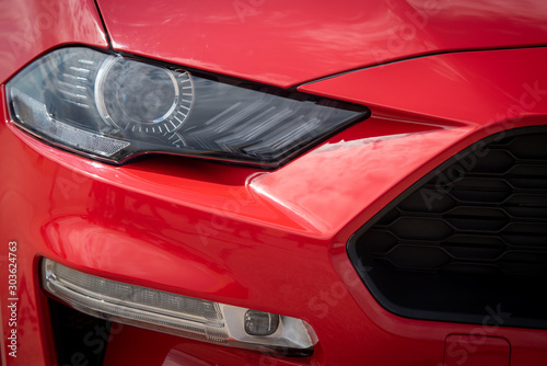 Metallic red surface details of the headlights of a luxury sports car