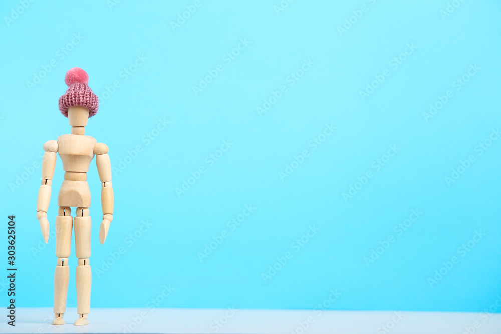 Wooden figure in pink hat on blue background Wooden figure in pink hat on blue background