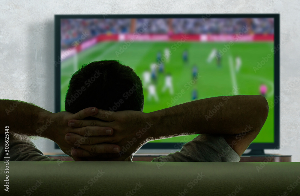 Φωτογραφία view from behind of young soccer fan man watching European football game on big