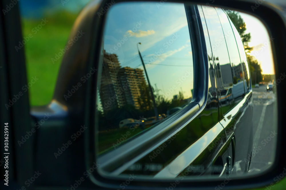 the body of the minibus reflected in the side mirror of the car