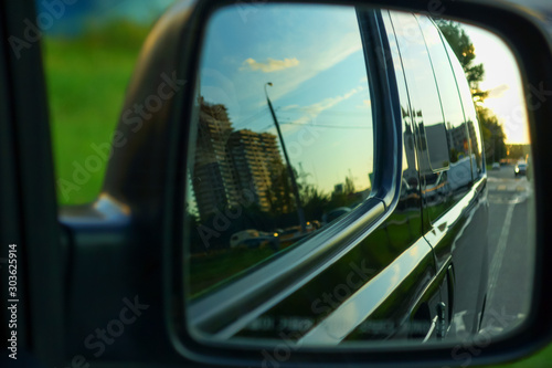 the body of the minibus reflected in the side mirror of the car © Elena