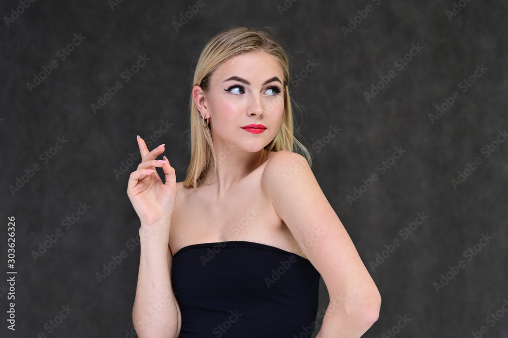 The concept of fashionable glamor, cosmetics and beauty with a pretty girl. Portrait of a fashionable beautiful blonde model with long hair, great makeup, on a gray background. The concept of fashionable glamor, cosmetics and beauty with a pretty girl. Portrait of a fashionable beautiful blonde model with long hair, great makeup, on a gray background.