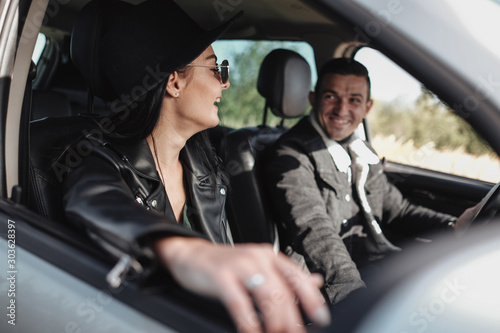 Happy Traveling Couple Dressed in Black Stylish Clothes Enjoying a Road Trip Sitting Inside the Car, Vacation Concept © Romvy