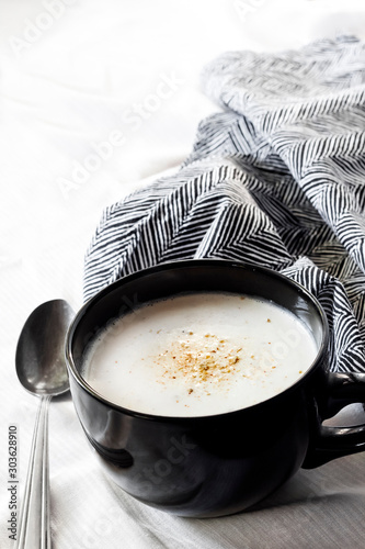 Cauliflower Soup (Creme du Barry) in black bowl on white background with black and white cloth photo