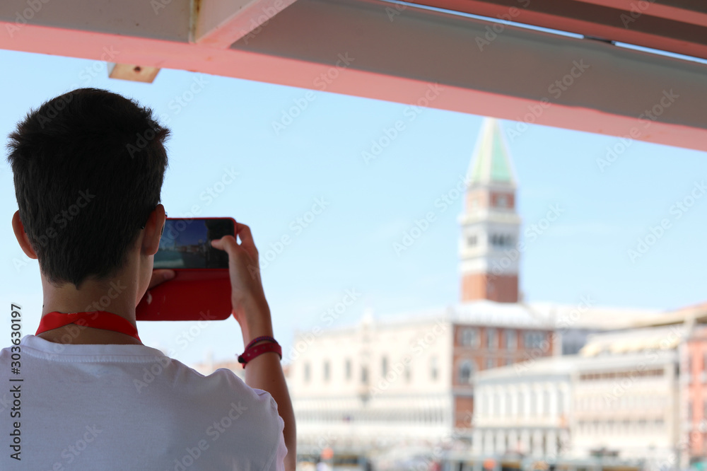 Φωτογραφία boy takes pictures at Bell tower of St Mark from the boat in Ven