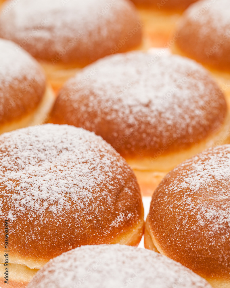 background of many Krapfen topped with icing sugar side by  side together