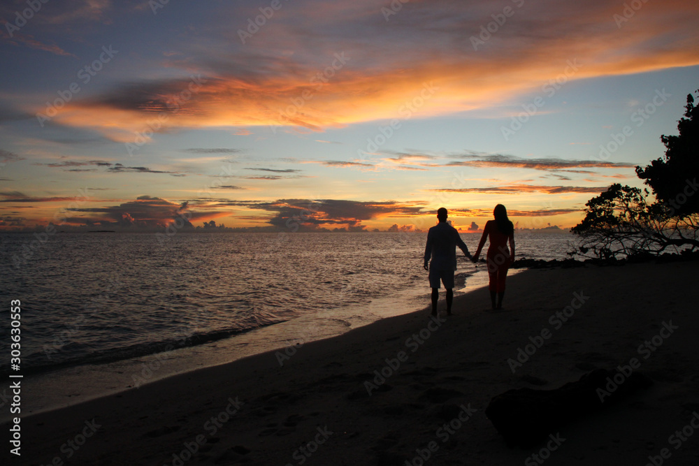 Silhouette of couple holding hands during sunset on a tropical beach