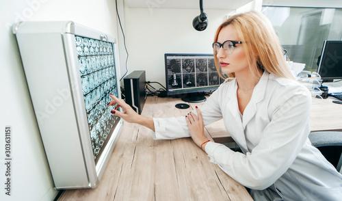 A professional doctor radiologist with gloves is looking at an mri picture on the background of a negatoscope photo