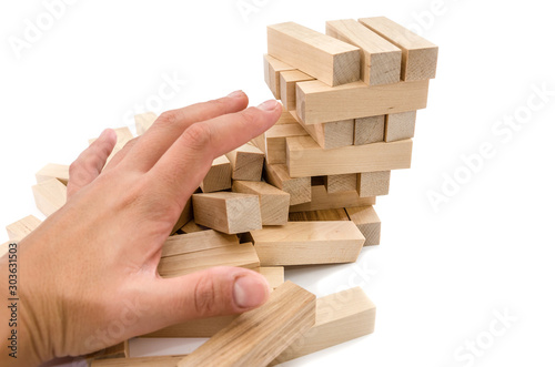 Planning, risk and strategy in business, hand gambling. Hand fells tower with blocks. Wooden blocks isolated on white background.