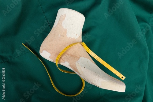 a wooden last on a green clobber with a measuring tape