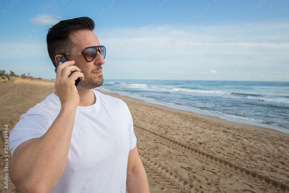 Man talking on the phone near to the beach and using new technologies. 
