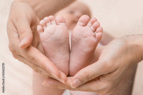 Children's feet in the hands of the mother. Mother and her Child. The concept of a happy family. Beautiful conceptual image of motherhood