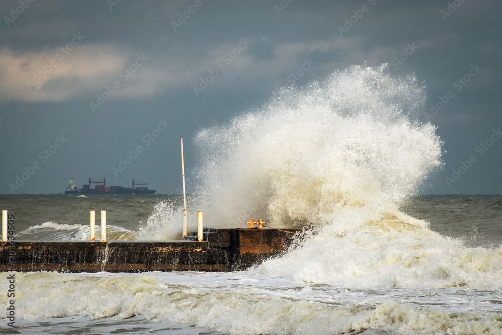 breakwater and harbour in stormy weather with huge waves crashing over the walls pier. Abnormally strong storms in the middle latitudes as a result of global warming.