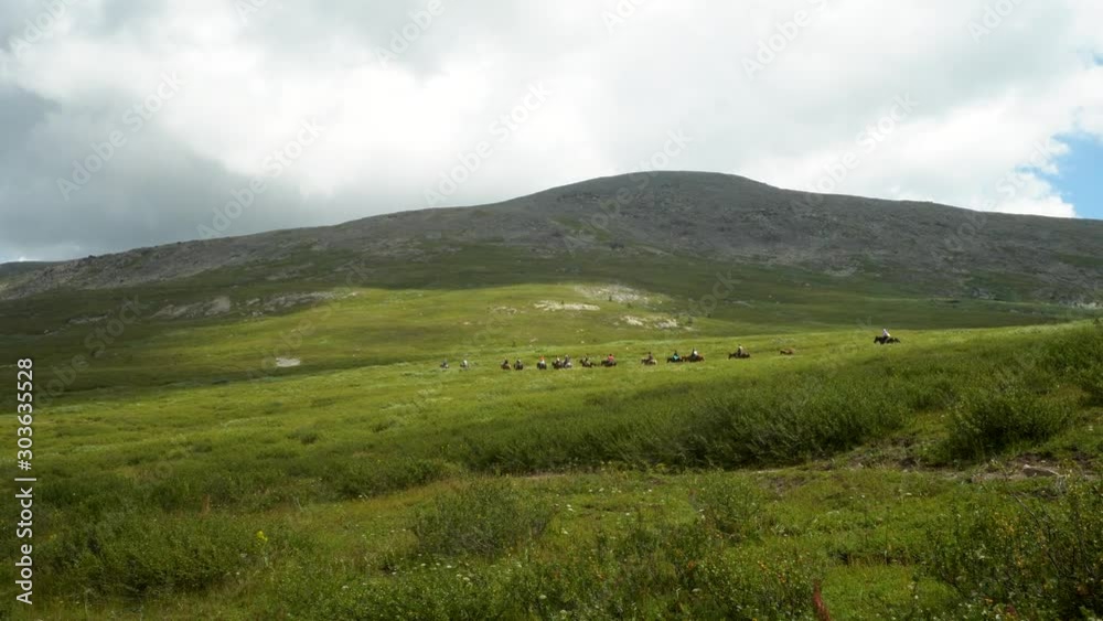 A large group of tourists on a horseback ride in the mountains in the summer. 4k footage. A large group of tourists on a horseback ride in the mountains in the summer. 4k footage.
