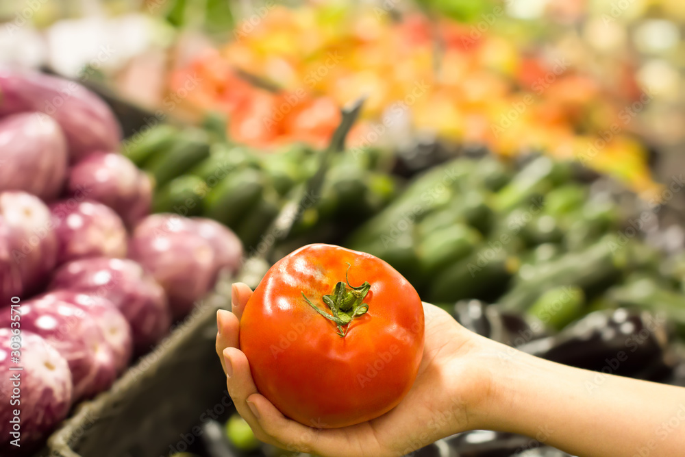 Female hand choosing tomato in supermarket. Concept of healthy food, bio, vegetarian, diet. Female hand choosing tomato in supermarket. Concept of healthy food, bio, vegetarian, diet.