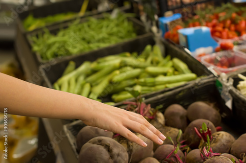 Female hand choosing beet root in supermarket. Concept of healthy food, bio, vegetarian, diet.