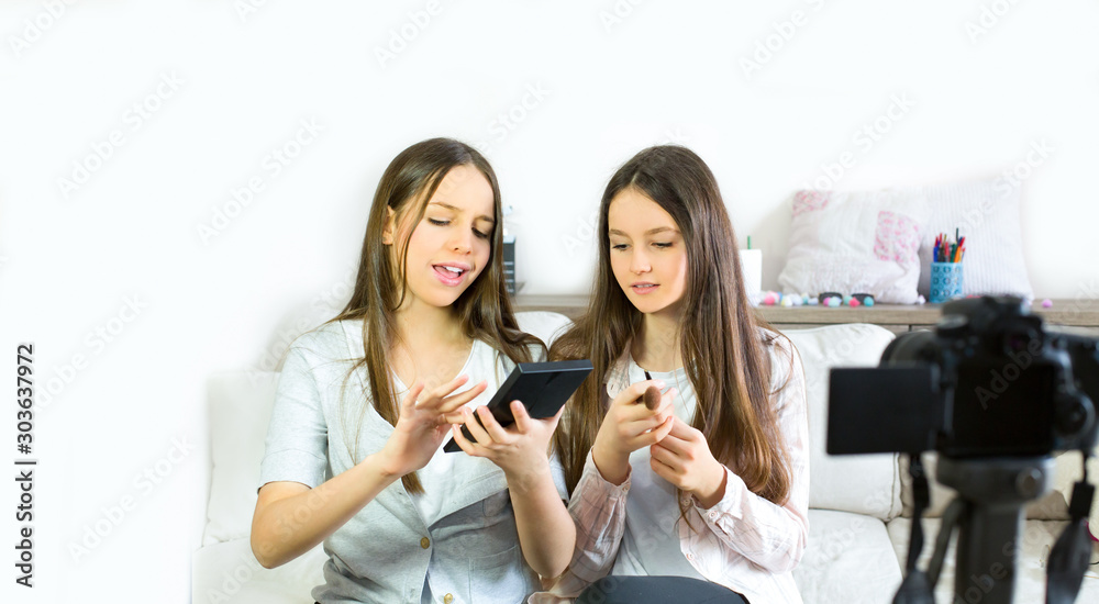 Two teen girls blogger presents beauty products and transmitting live video to social networks. Focus on the influencer of teenage blogger girls. Beauty blogger and vlog concept. Two teen girls blogger presents beauty products and transmitting live video to social networks. Focus on the influencer of teenage blogger girls. Beauty blogger and vlog concept.
