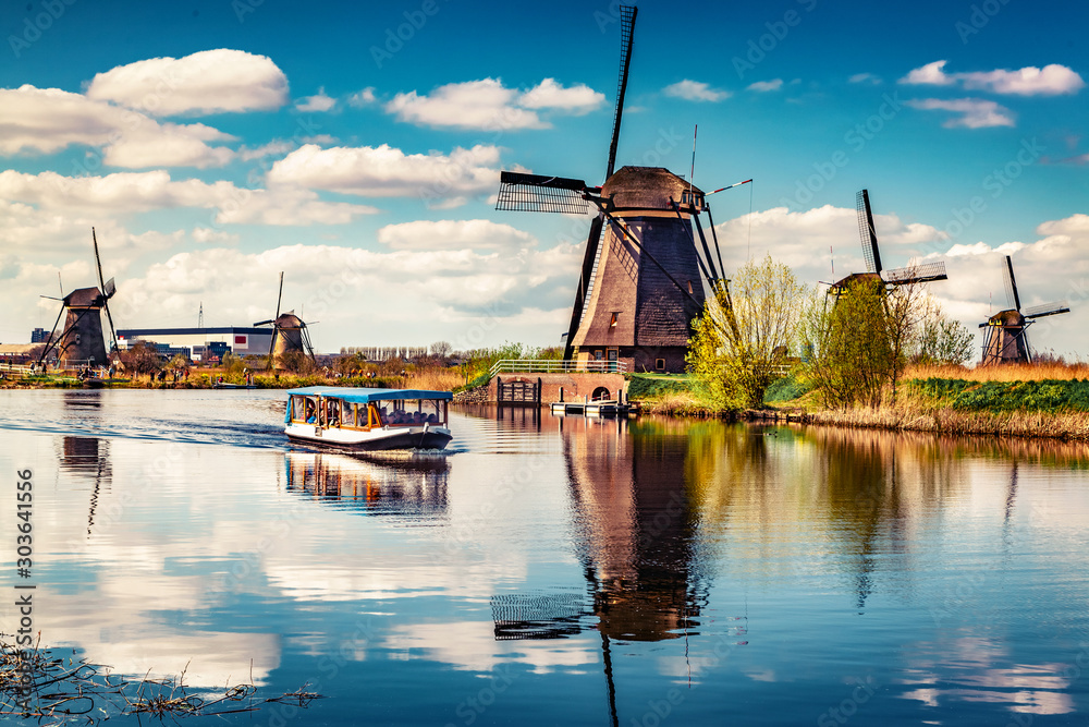 Walking boat on the famoust Kinderdijk canal with windmills. Old Dutch village Kinderdijk, UNESCO world heritage site. Netherlands, Europe. - obrazy, fototapety, plakaty 