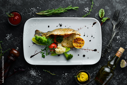 Baked trout fillet with vegetables on a plate. Top view. Free copy space. photo