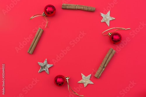 Christmas circle composition. Wreath of stars, cinnamonand toys on red background. Winter wedding design. Flat lay, top view.