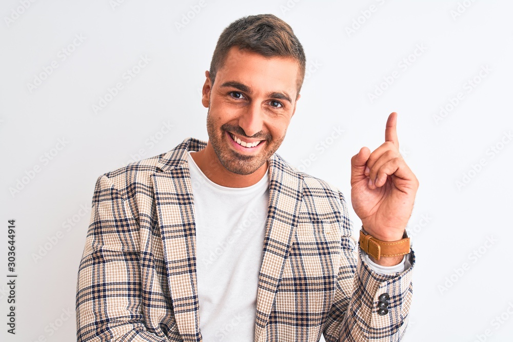 Naklejka premium Young handsome business man wearing elegant jacket over isolated background with a big smile on face, pointing with hand and finger to the side looking at the camera.