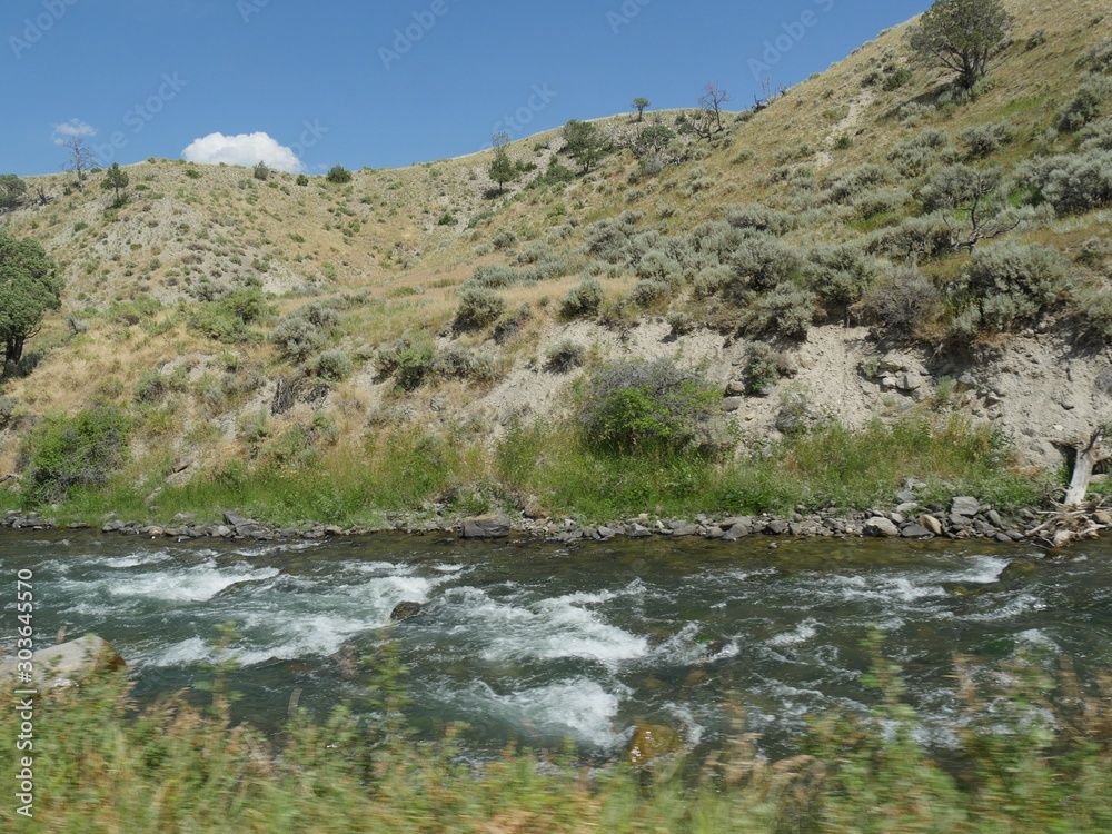 Close up of the Yellowstone River flowing along the road and right next to a rocky mountain toward Gardiner, Montana. Close up of the Yellowstone River flowing along the road and right next to a rocky mountain toward Gardiner, Montana.