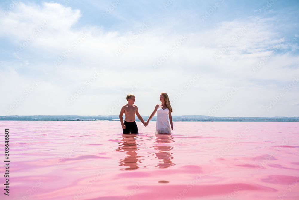 cute teenager couple walking on a shore of amazing pink lake