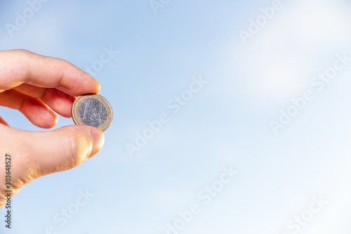 hand holding 1 euro coin over clear blue sky, Exchange money. Financial concepts, Business Concept.