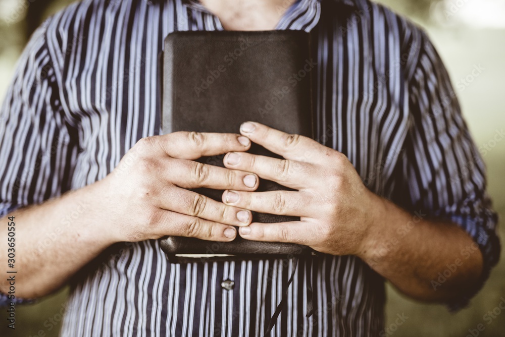 Φωτογραφία Closeup shot of a male holding the bible against his chest with a blurred backgr