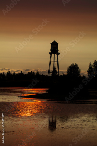 Weldwood water tower silhouetted against the evening sun with a red cast from California wildfires. 