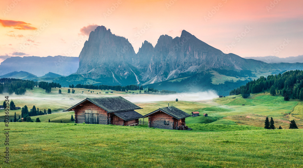 Superb morning scene of Compaccio village with huge rainbow on background, Seiser Alm or Alpe di Siusi location, Bolzano province, South Tyrol, Italy, Europe. Colorful summer sunrise of Dolomiti Alps.