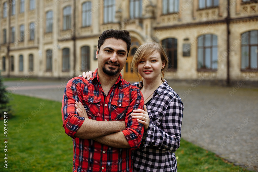 Loving couple in plaid shirts, against the background of the university