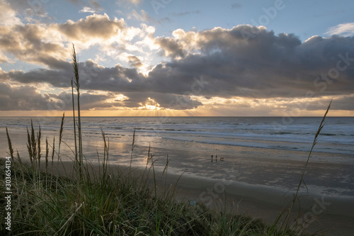 The sun peeks from behind a cloud in the evening at Newport, Oregon.