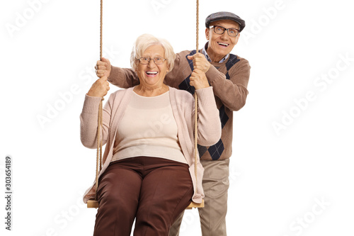 Elderly man pushing an elderly woman on a swing